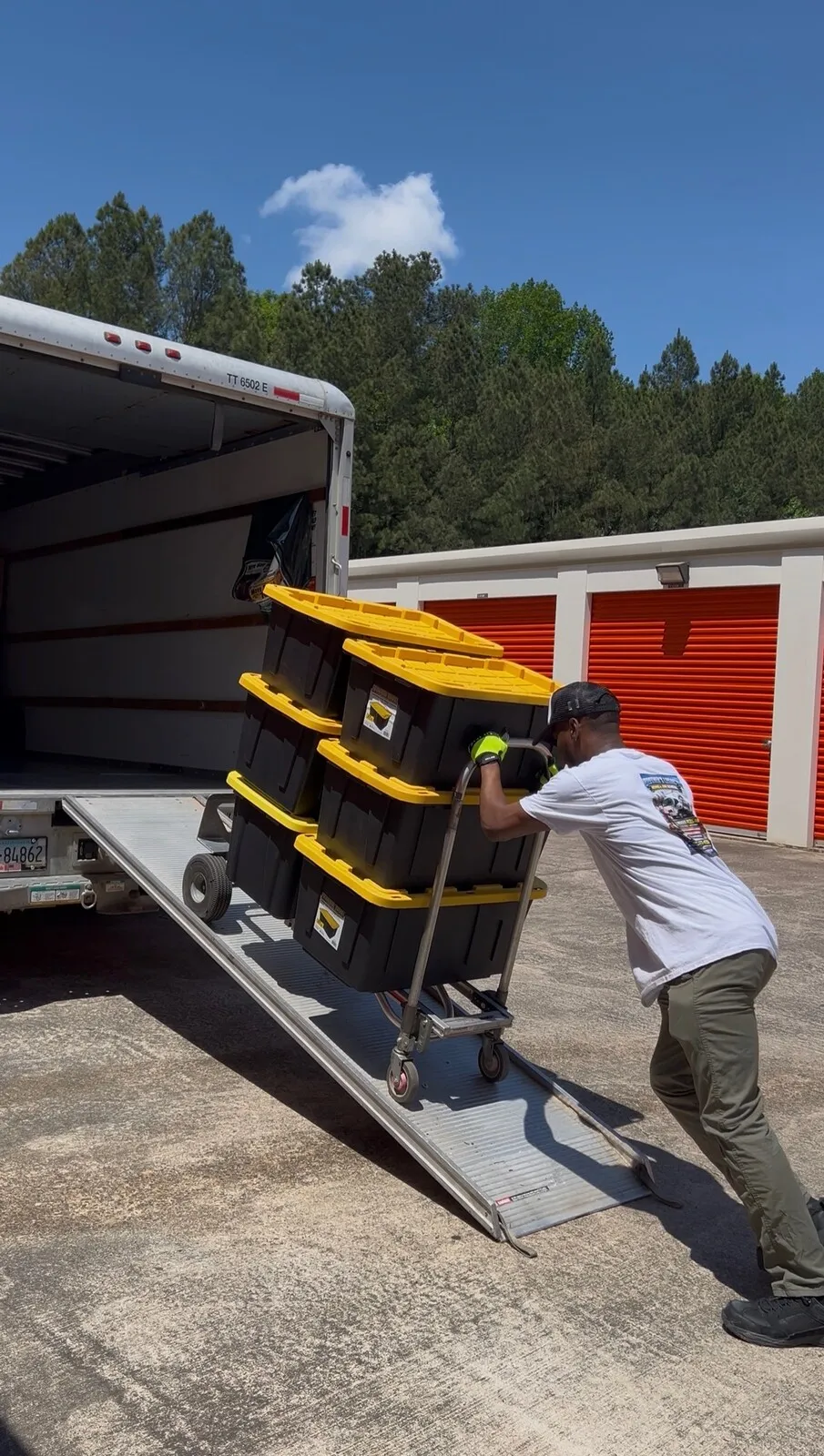 The Brothers Legacy crew hauling loaded totes up a truck ramp outdoors