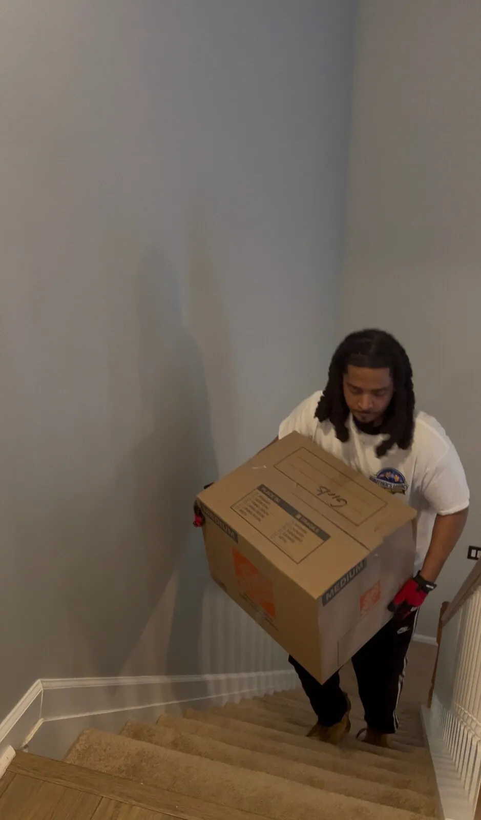 A crew member carefully carrying a box inside a home